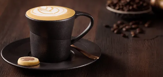 Cappuccino in black cup with biscuit
