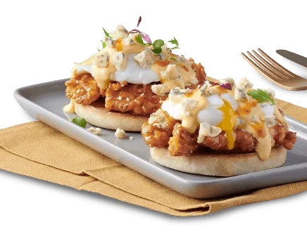 Eggs Benedict meal on a serving plate with utensils alongside
