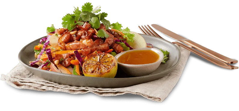 Crispy Pork Salad on plate with utensils alongside Crispy Pork Salad on plate with utensils alongside