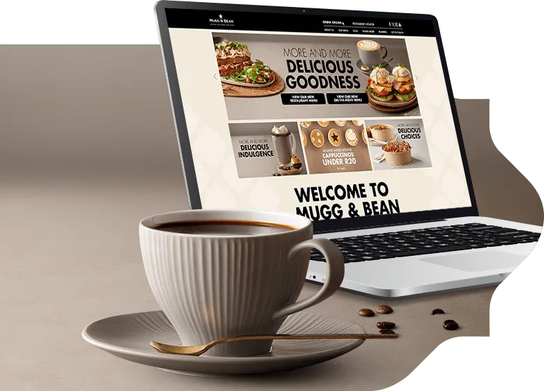 A cup of coffee on a side plate alongside a laptop computer A cup of coffee on a side plate alongside a laptop computer