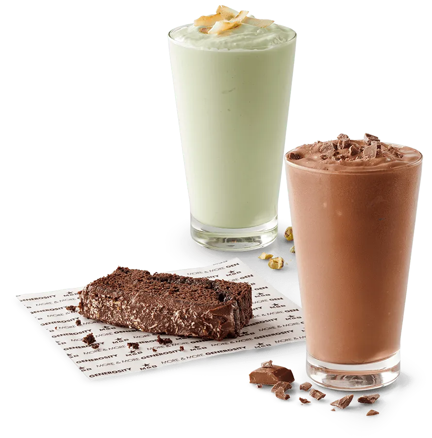 Two plant based milkshakes with a slice of chocolate cake on a white background Two plant based milkshakes with a slice of chocolate cake on a white background