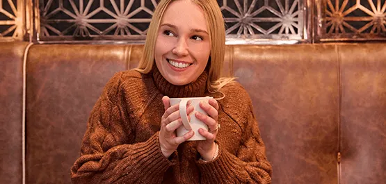 A a blonde women warming up with a cup of coffee