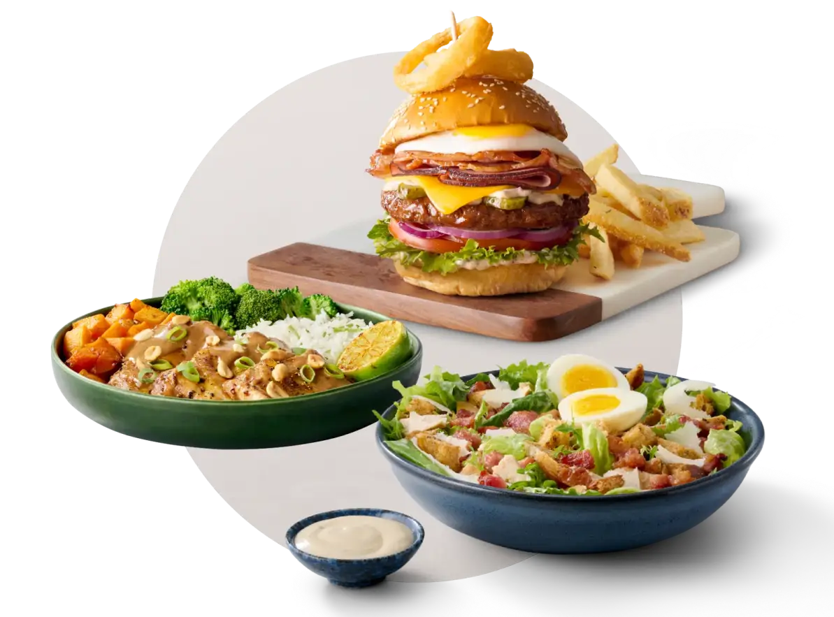 A stacked Mugg & Bean gourmet burger with fries, a chicken and vegetable rice bowl and a chicken Caesar salad