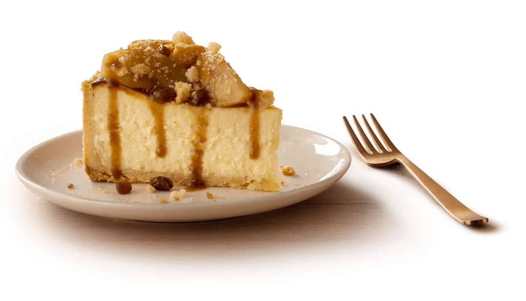 A slice of apple pie cheesecake with a crumbly base and caramel drizzle A slice of apple pie cheesecake with a crumbly base and caramel drizzle