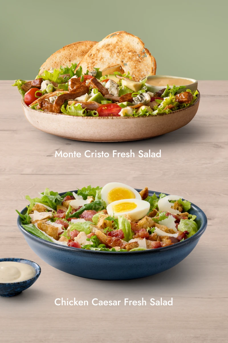 Two fresh salads — Monte Cristo Fresh Salad and new Asian Crispy Veg Fresh Salad — served in bowls with a side of dressing.