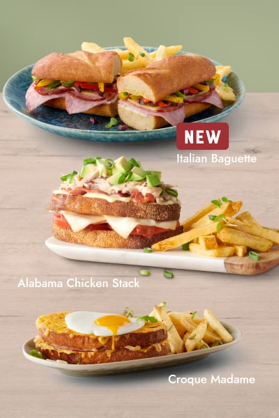Three gourmet sandwiches — Italian Baguette, Alabama Chicken Stack, and Croque Madame — each served with fries on separate plates.